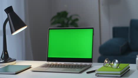 Arbeitstisch-Im-Heim-Laptop-Mit-Chroma-Key-Display,-Lampe,-Brille-Und-Büchern.-Mann-Schaltet-Stehlampe-Im-Hintergrund-Der-Wohnungseinrichtung-Ein